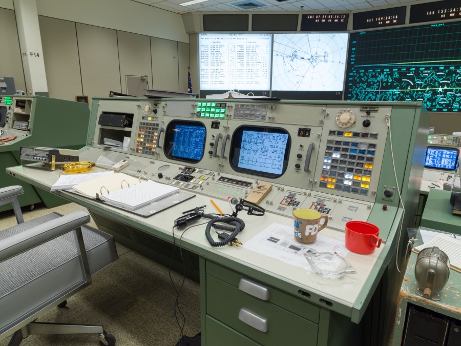 Illuminated screens and switches on a restored Apollo mission control console.